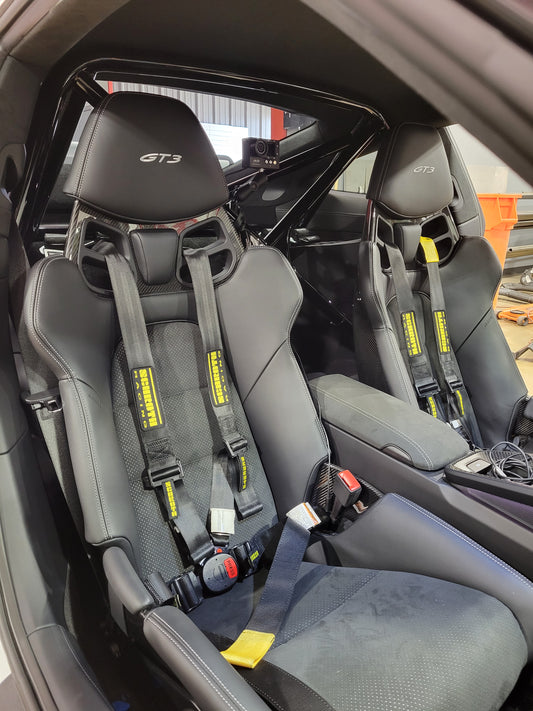 Porsche GT3 interior showing racing seats with harnesses and roll bar for enhanced safety and performance.