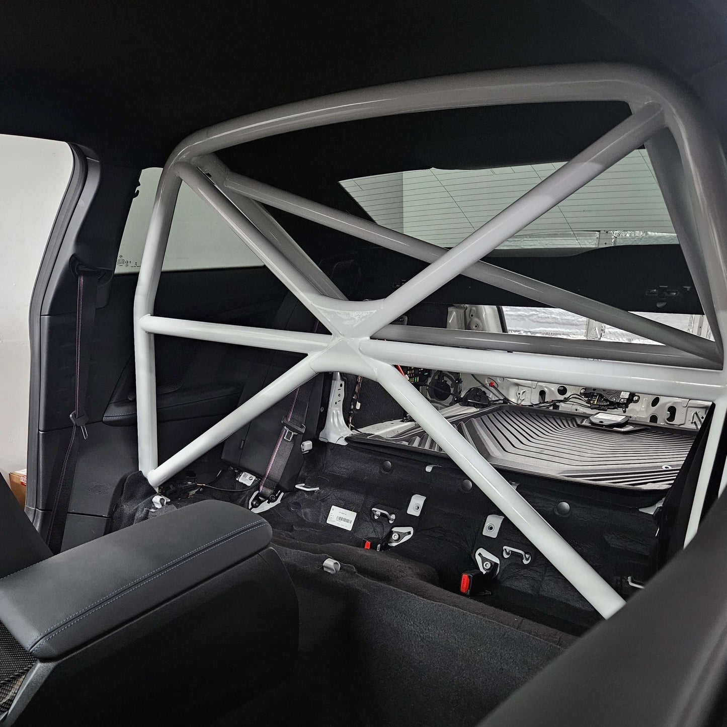 WPM G87 M2 Clubsport Half Cage showing a white safety roll cage inside the car's rear interior.