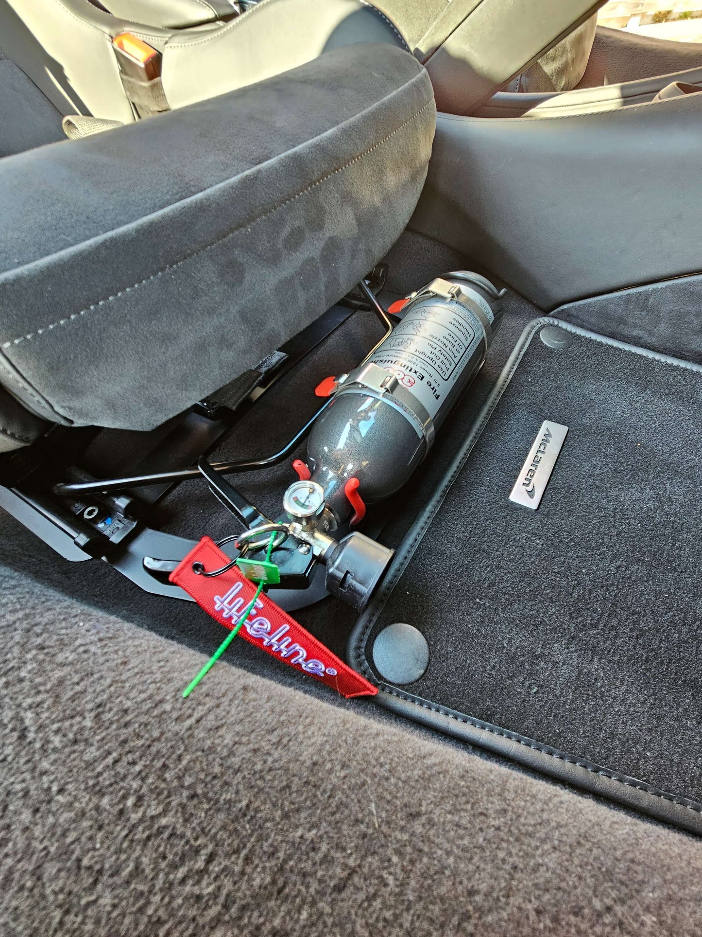 Mclaren Lifeline Novec handheld fire bottle mounted underseat with bracket for easy access and safety.