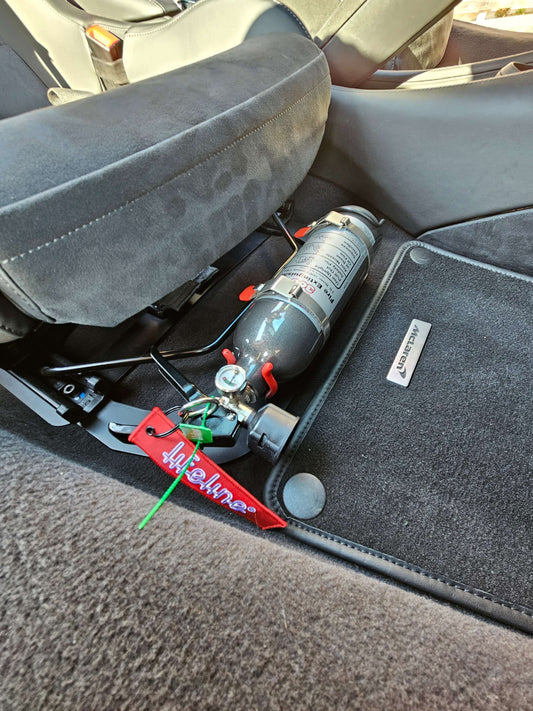 Mclaren Lifeline Novec handheld fire bottle mounted underseat with bracket for easy access and safety.