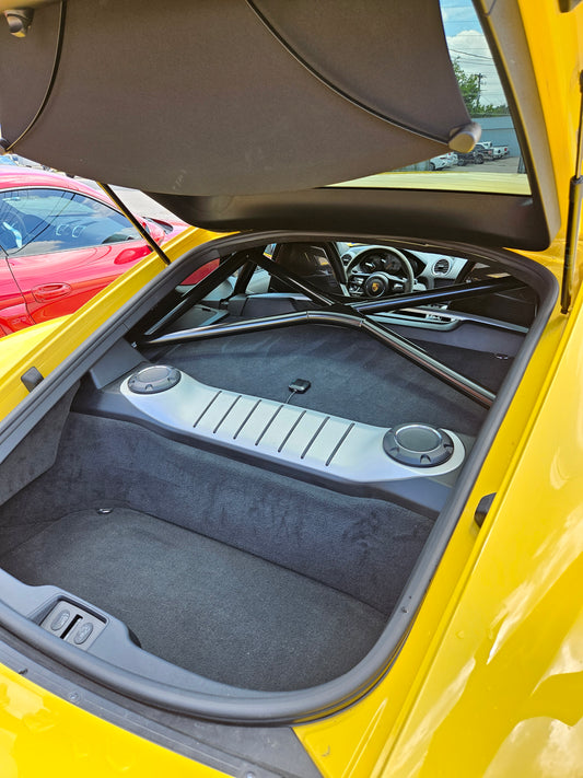 Interior view of a yellow Porsche Cayman showcasing its roll bar and sleek design.