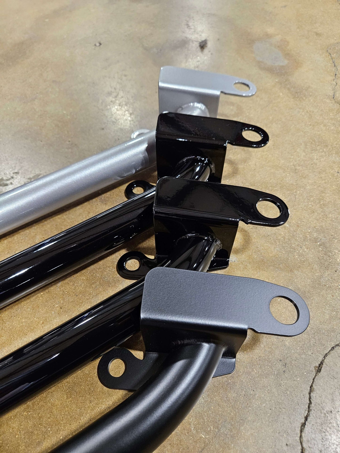 Close-up view of Porsche 981/982 harness bar in black and silver, showcasing high strength construction and factory mounting brackets.
