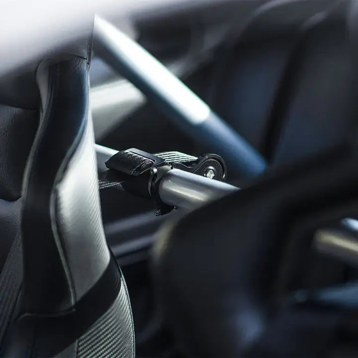 RS Pro harness collar securing a seat belt on a roll cage in a racing car interior.