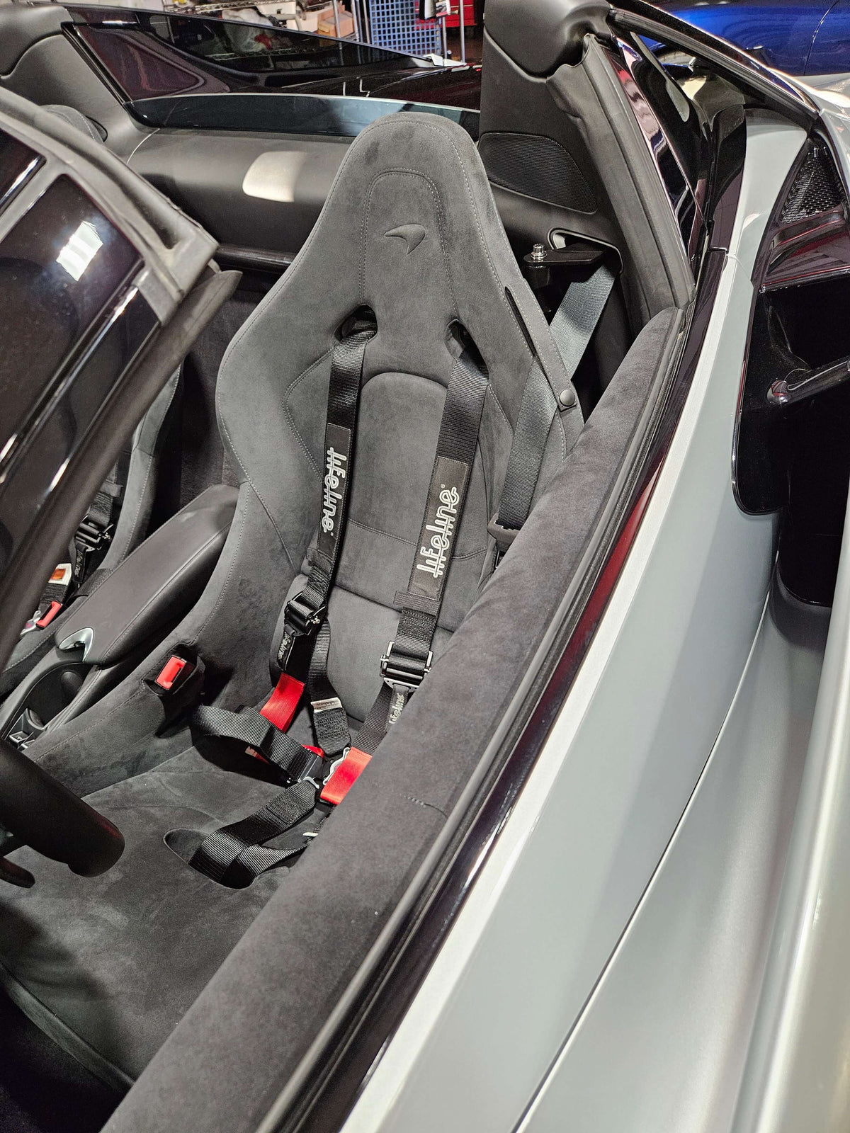 Mclaren 720S Spider interior featuring racing harness and custom seat, showcasing a secure and stylish setup.