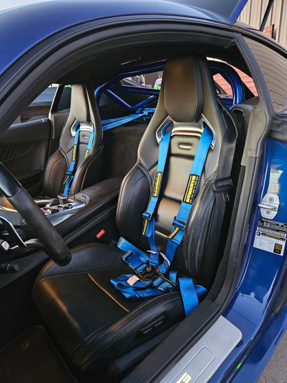Interior of a Mercedes AMG GT showing bolt-in roll bar and blue 6-point harnesses for enhanced safety.