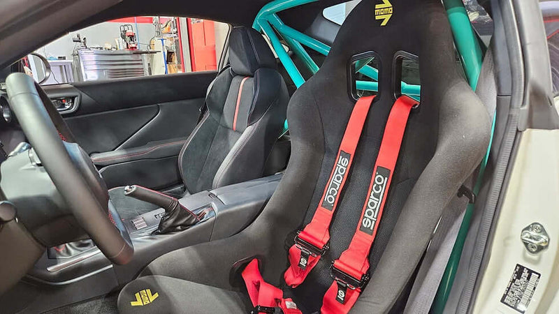 Interior view of a GR86 with a Sparco racing seat, 5-point harness, and custom roll bar for enhanced safety.