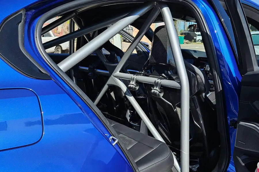WPM G80 M3 Clubsport half cage view from inside a blue car, showcasing its sturdy design and seatbelt mounts.